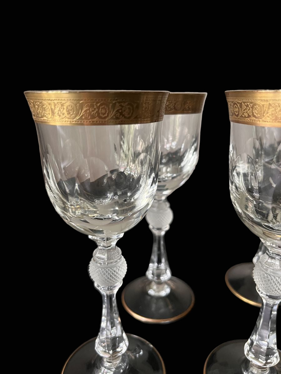 Set of crystal glasses with gold accents on a dark surface.