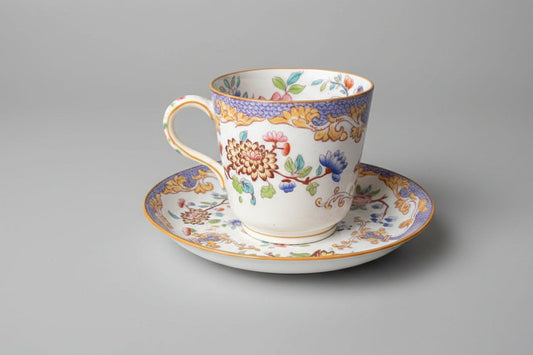 Decorative teacup and saucer with floral patterns on a gray background