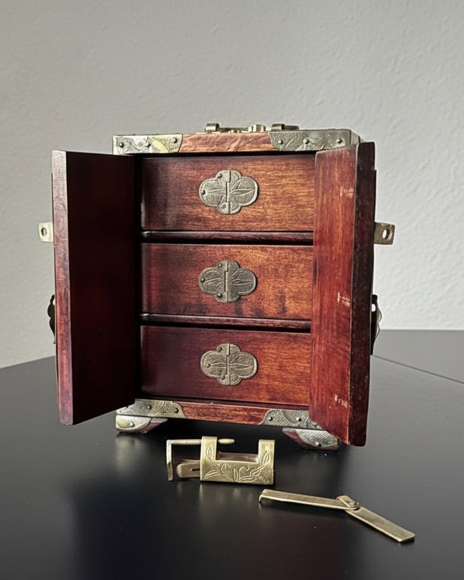 Wooden jewelry box with brass hardware on a dark surface