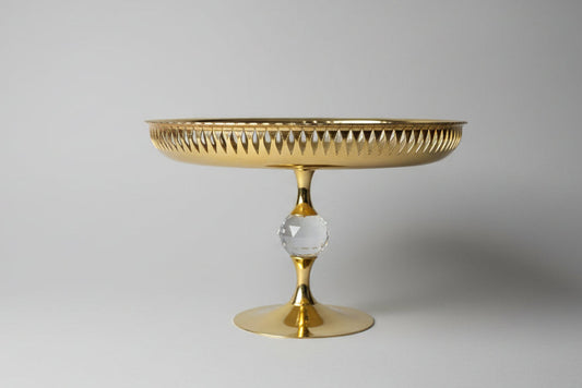 Gold decorative stand with a textured top and crystal base on a dark surface.