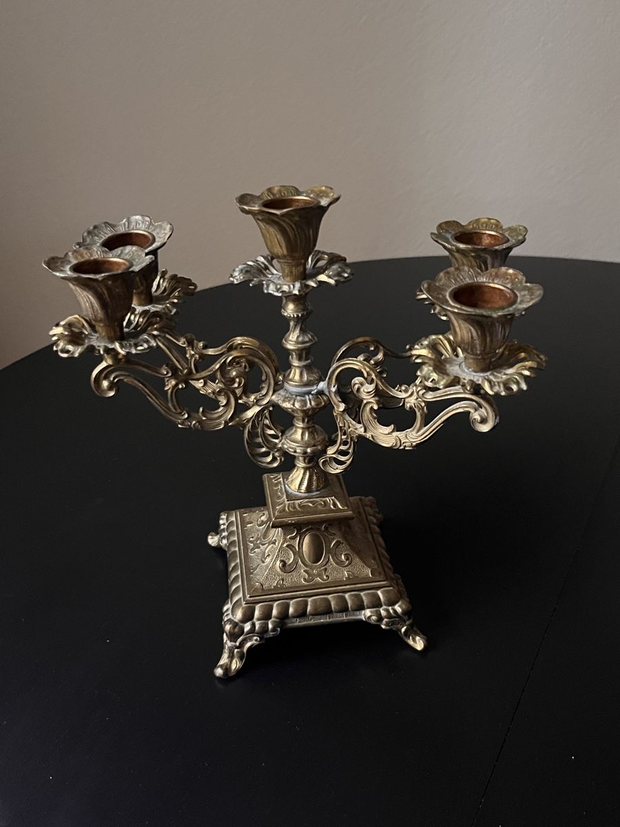 Silver candelabra on a black surface with a neutral background
