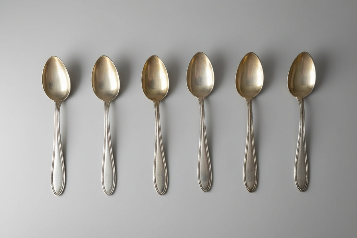 Set of six silver spoons on a black background
